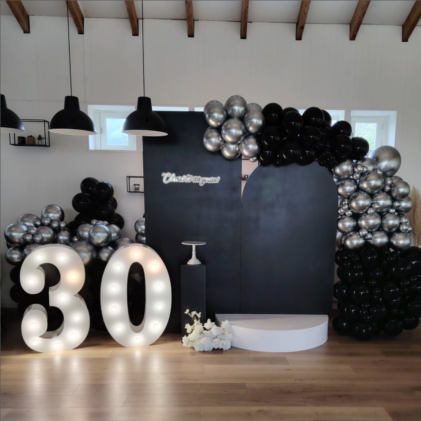 Décoration anniversaire 30 ans avec chiffres illuminés, ballons noirs et argentés et photocall élégant
